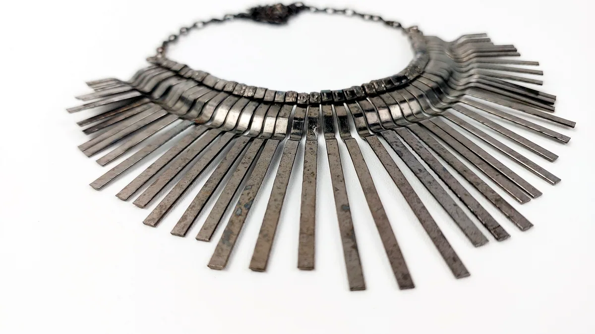 Three silver necklaces of different lengths layered on a dark display bust, the chains overlapping in a cascade.