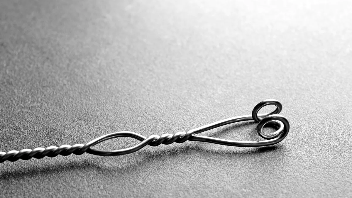 A spool of fine silver wire and a pair of cutters on a dark jewellers bench, tools ready for the next piece.