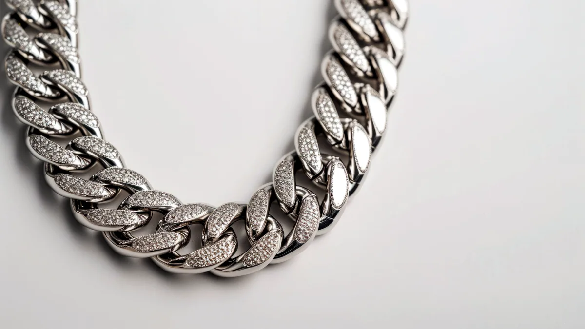 A length of sterling silver link chain coiled loosely on charcoal, each oval link reflecting a line of cool light.