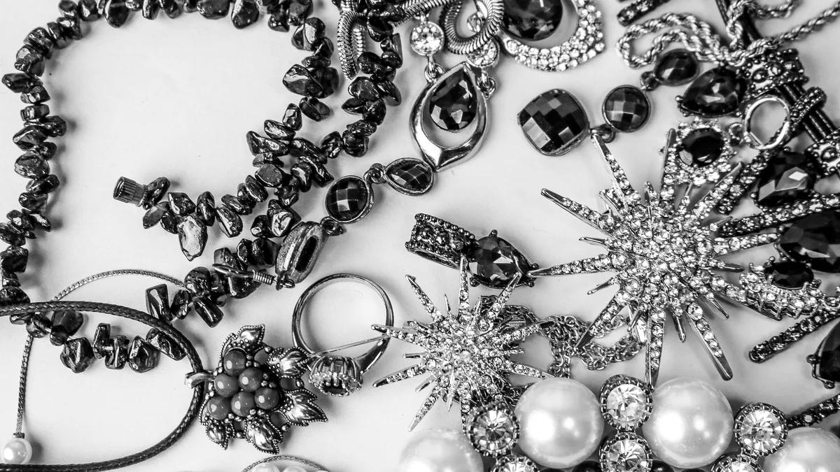 Several silver pieces in a flat lay on dark charcoal, all lit by one cool studio light.