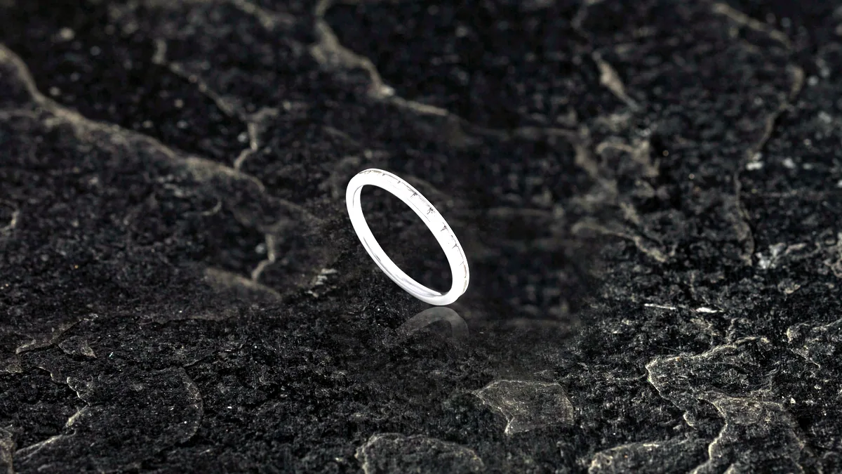 A simple 925 sterling silver ring centred on a dark charcoal tile, its shadow falling to the right.