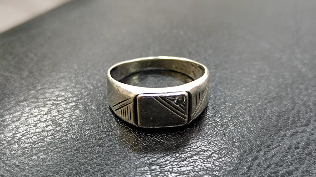 A silver ring with a dull grey patina along its inner surface, the tarnished side contrasting the polished outer face.